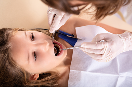 Close-up Of Girl Being Checked By Dentist With Dental Mirror And Scaler